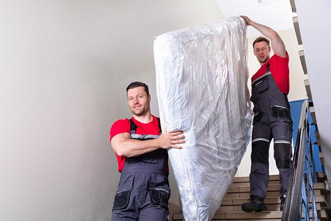 two workers lifting a box spring out of a bedroom in Freeland, WA